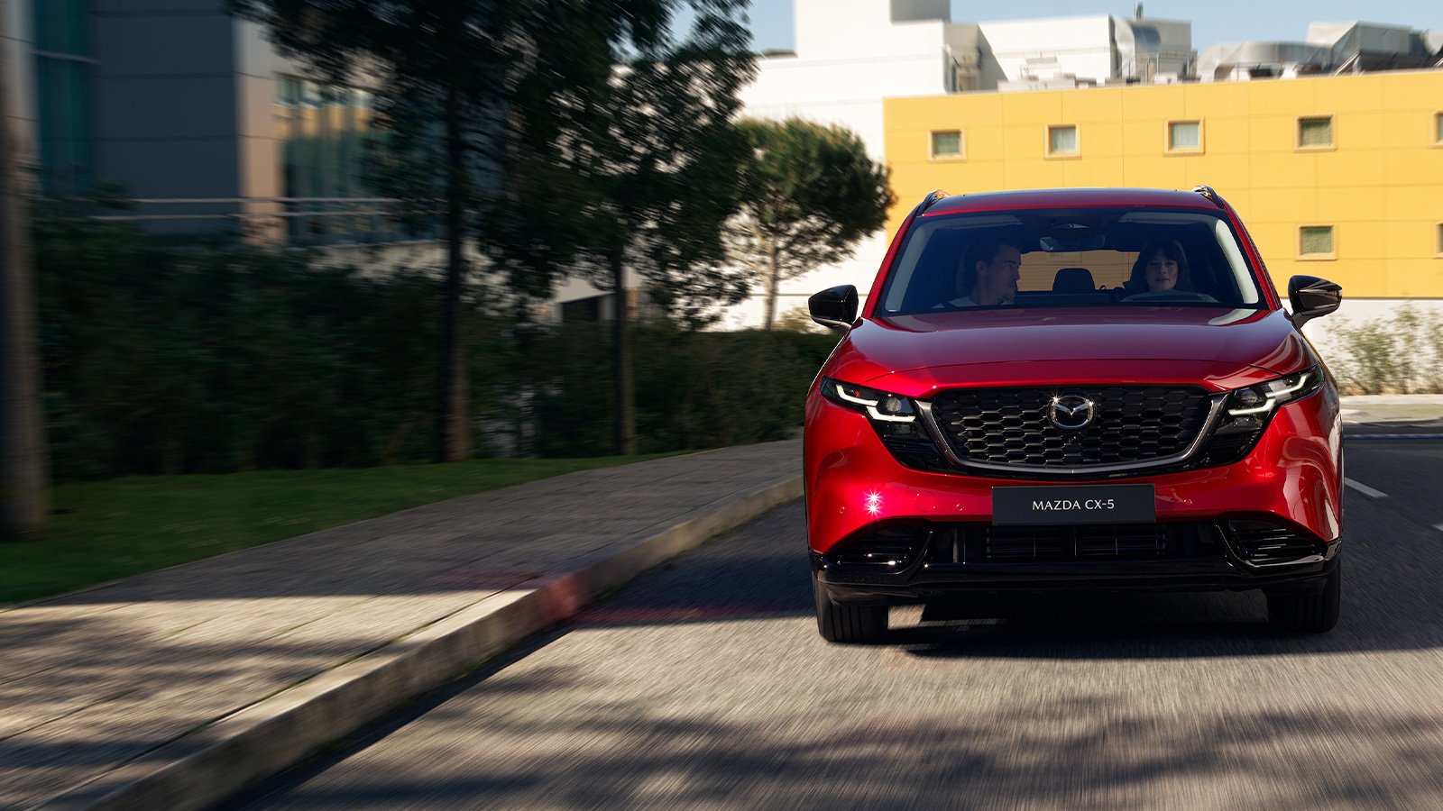 Front view of a Soul Red Crystal Mazda CX-5 driving towards the camera on a city road.