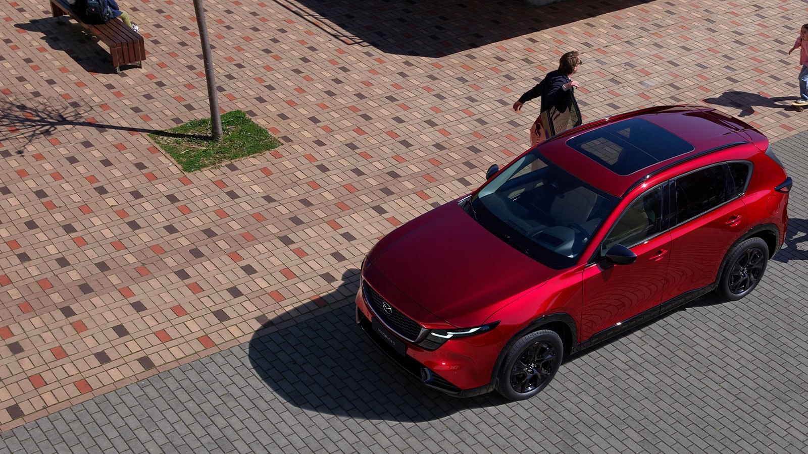 A Soul Red Crystal Mazda CX-5 shown from a top front side profile, parked as a man gets out.