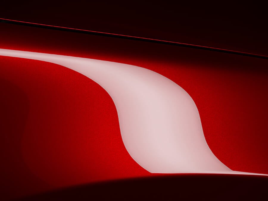 Détail du capot d’une Mazda rouge vibrant cristal reflétant la lumière.