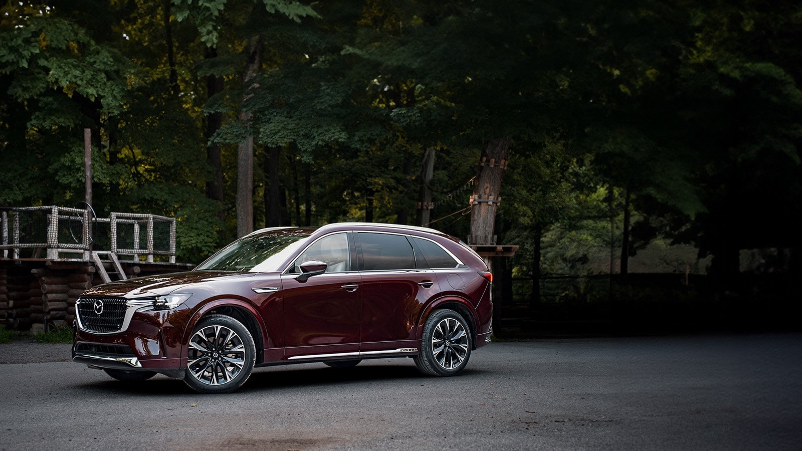 Un CX-90 rouge. On peut voir une zone suburbaine en arrière-plan.