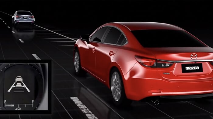 Une Mazda rouge sur la route utilisant le régulateur de vitesse pour maintenir une distance sécuritaire avec la Mazda grise devant elle