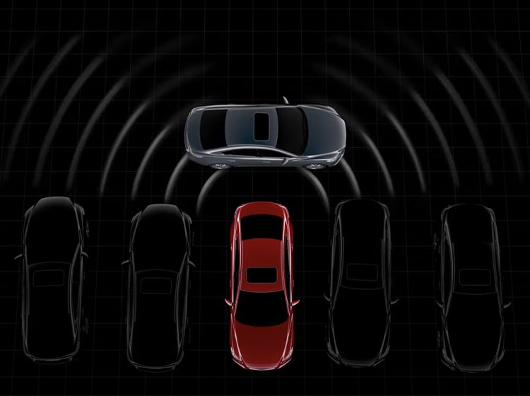 Vue aérienne d’une Mazda rouge reculant d’une file de voitures stationnées, de côté, avec le capteur radar à ondes millimétriques détectant des voitures qui doublent.