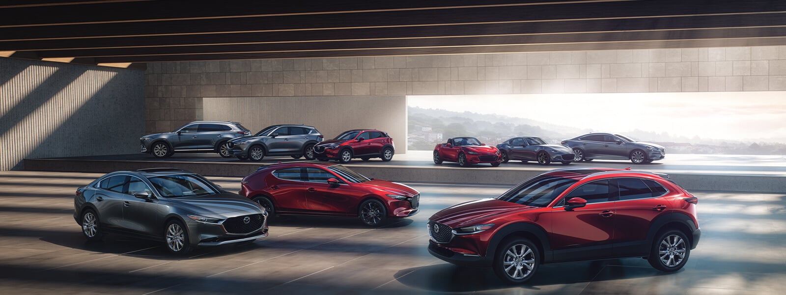 Divers modèles Mazda dans une salle d’exposition, dont une berline Mazda3, une Mazda6 et un CX-5.