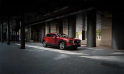 Red Mazda3 Sport parked in front of grey columns 