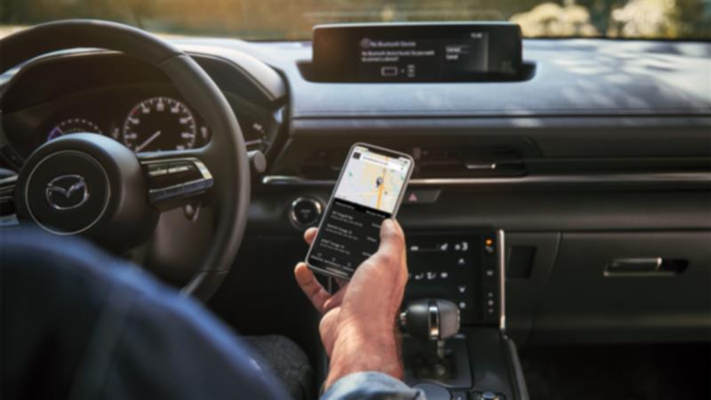 Propriétaire Mazda connectant son téléphone à la voiture.