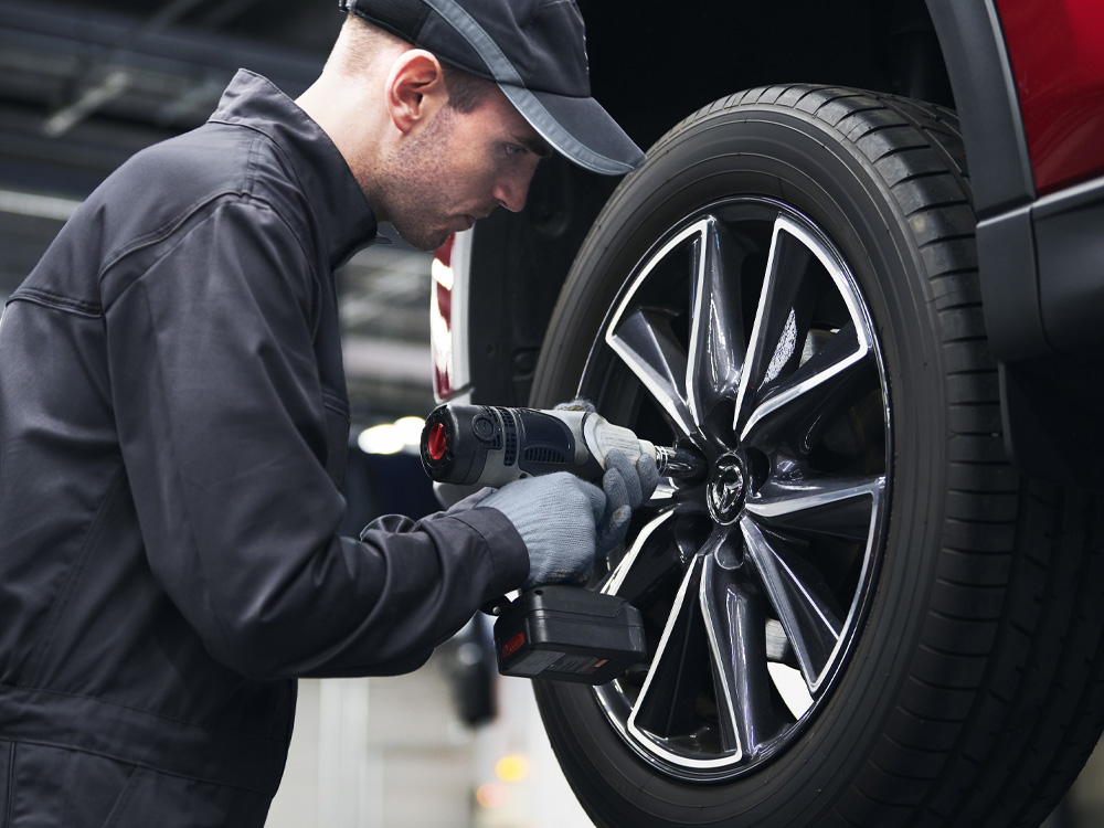 Mazda technician tightening lug nuts on wheel of vehicle