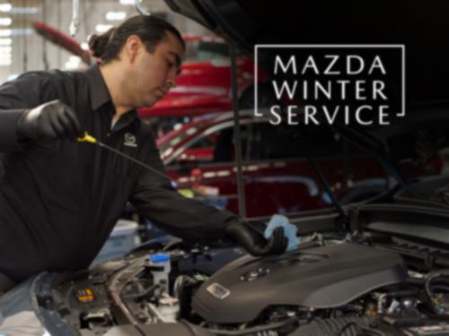 A Mazda Technician checking the oil on a vehicle