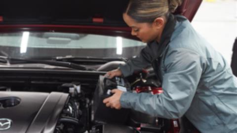 A Mazda technician working on a vehicle's brakes