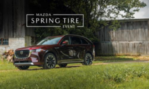 A red Mazda CX-90 parked on a grassy field