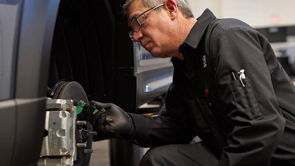 Un technicien de Mazda qui travaille sur les freins d’un véhicule