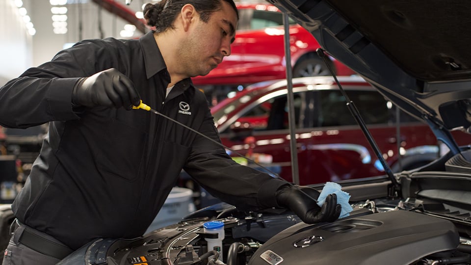 Un technicien de Mazda vérifiant l'huile d'un véhicule