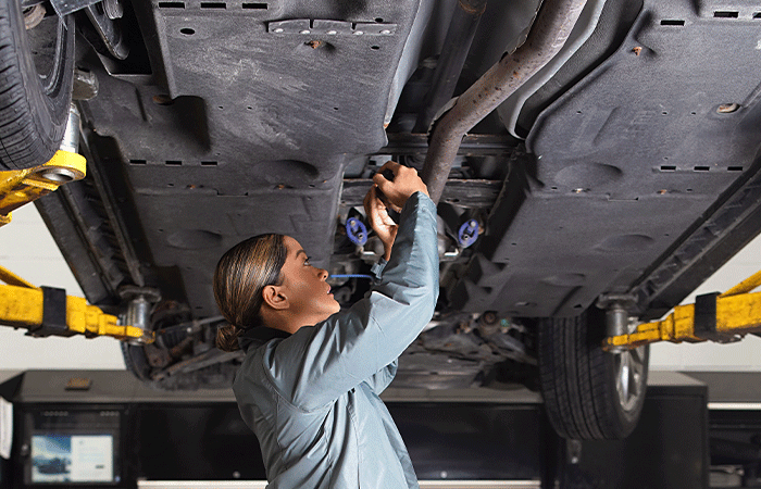 A Mazda technician working under a vehicle