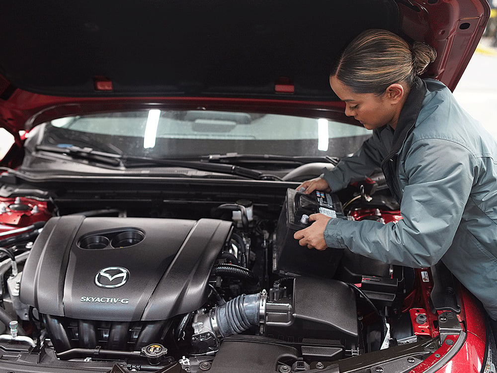 Un technicien de Mazda qui travaille sur le moteur d’un véhicule