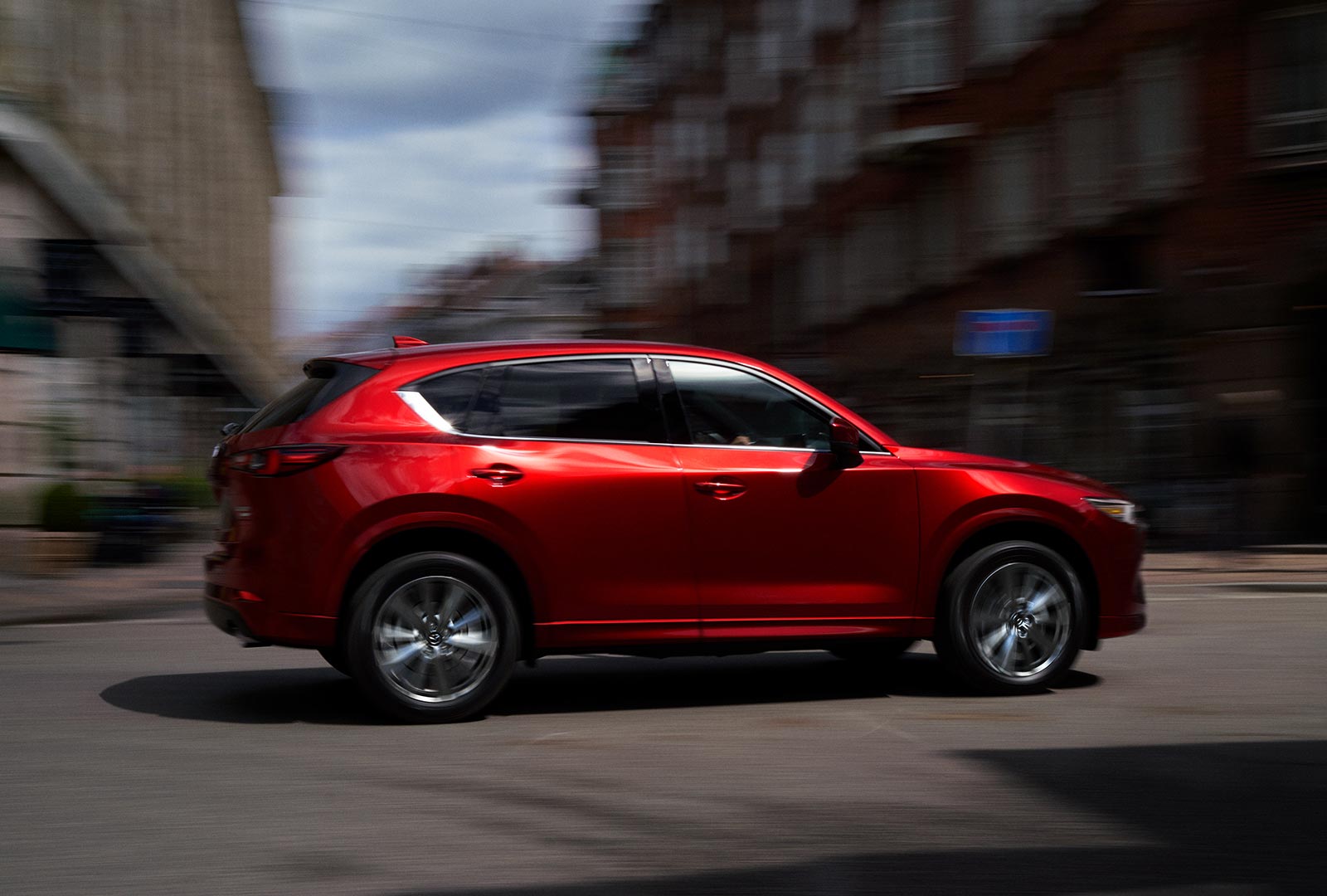 Soul Red Crystal CX-5 blurred profile as it moves along urban street.
