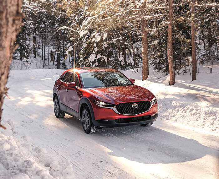 Soul Red Crystal Metallic Mazda CX-30 glimmers in the sun on a snowy country road.