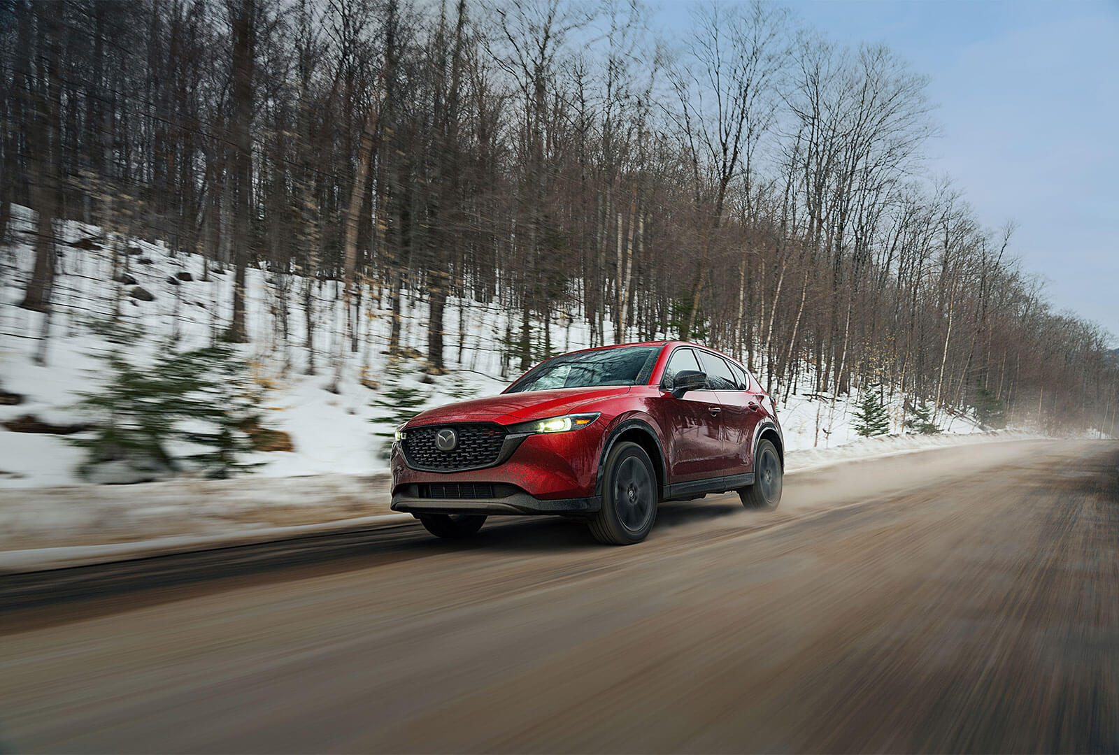 Soul red metallic CX-5 driving down wintery country road.