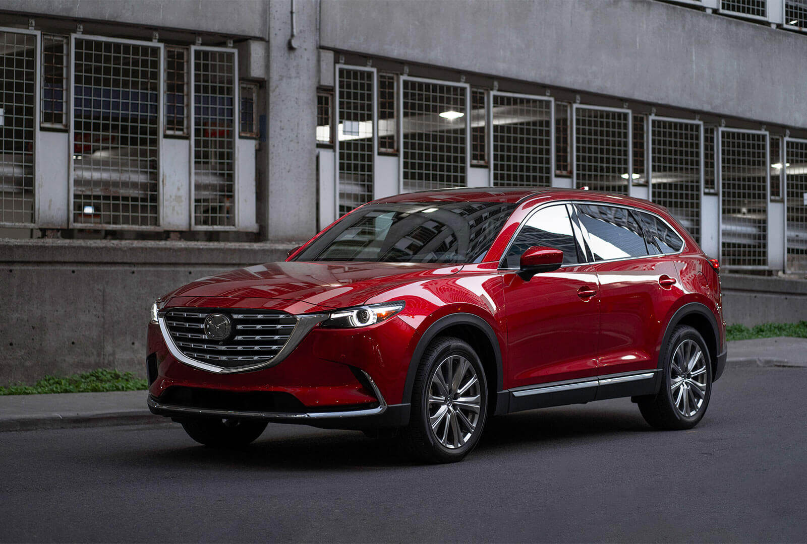 Red CX-9 stopped in front of parking garage.