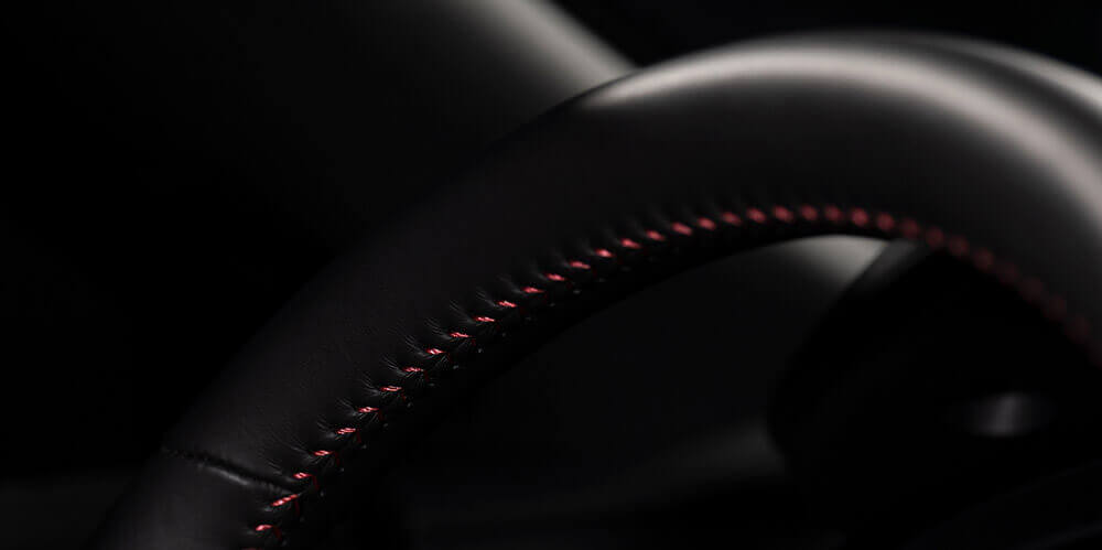 Black leather steering wheel with red stitching accents