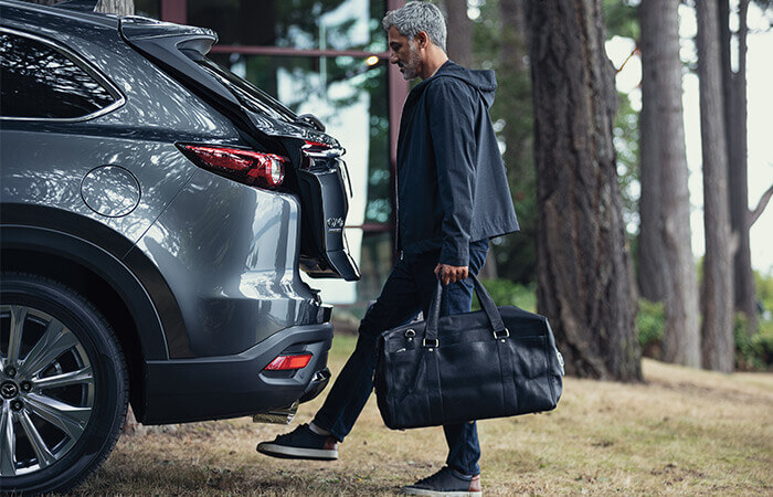 Adult holding travel bag lifts foot to activate rear liftgate.