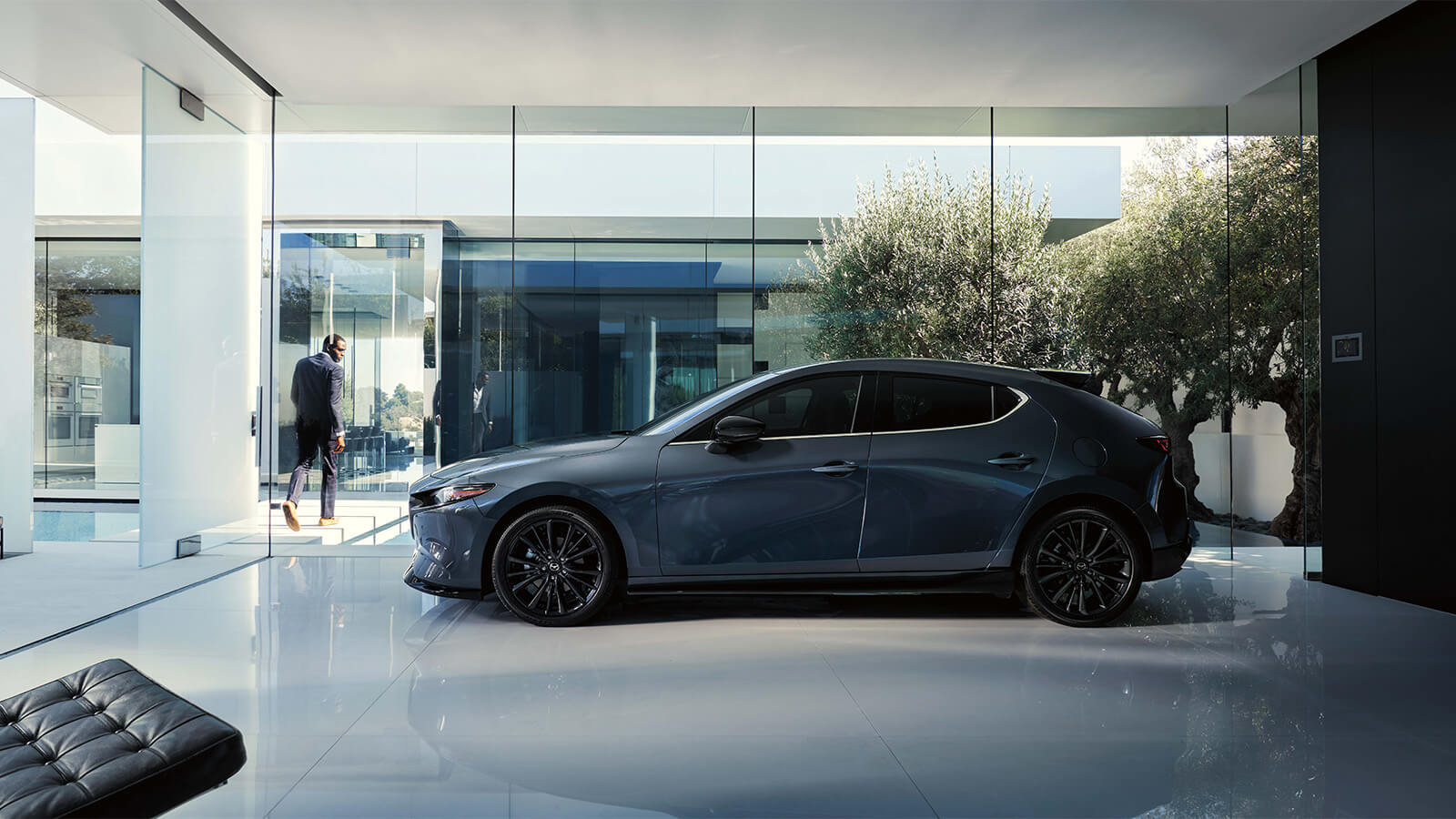 Polymetal Grey Mazda3 Sport hatchback is parked in a glass surround garage. 
