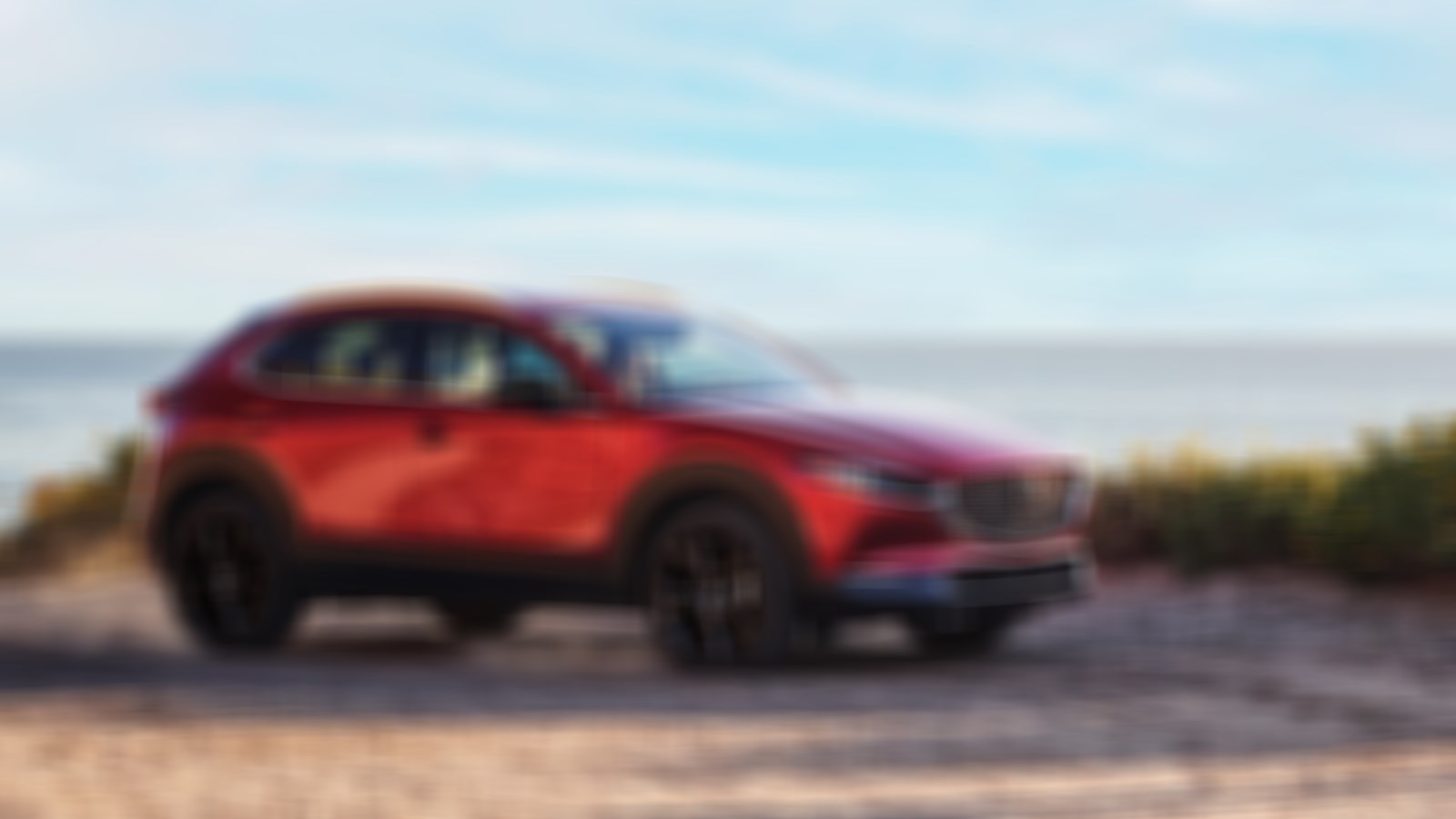Soul Red Crystal Metallic CX-30 Parked on sandy landing overlooking a vast lake.