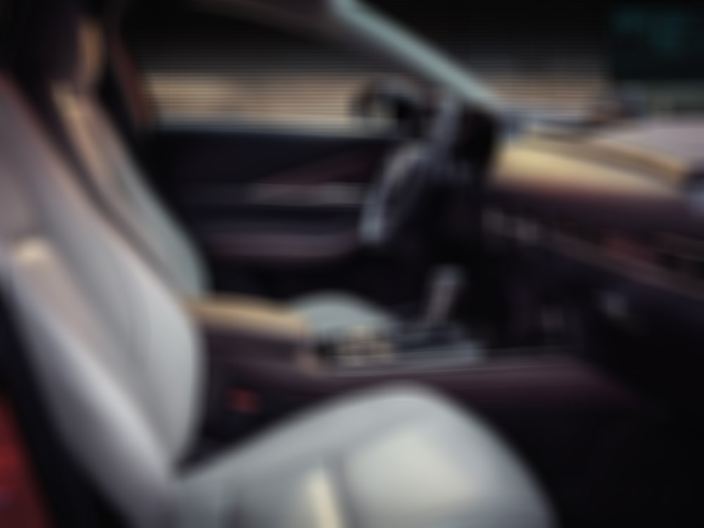Vue du côté passager à l’intérieur d’un CX-30; la lumière matinale brille sur le tableau de bord et les sièges en cuir Nappa blanc. 