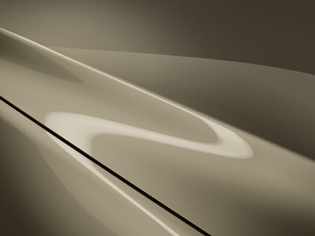 Gros plan sur le capot d’un CX-5 sable de zircon métallisé, les reflets de l’éclairage accentuent ses courbes.