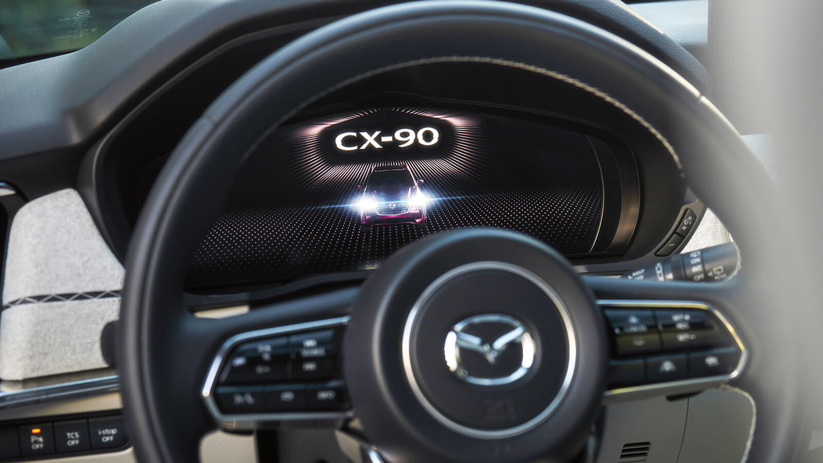 Closeup of display behind the wheel, CX-90 animates as the vehicle starts.  