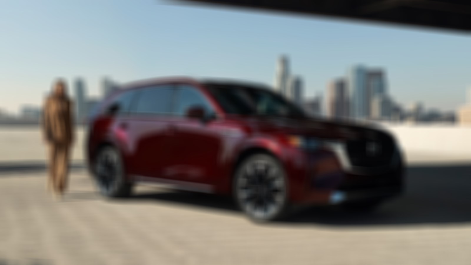 Driver in tan suit reaches for driver’s seat door of   Artisan Red CX-90 PHEV.