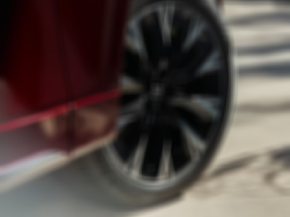 Closeup of 21-inch alloy wheel with machined spokes, polished finish and dark painted pockets. 