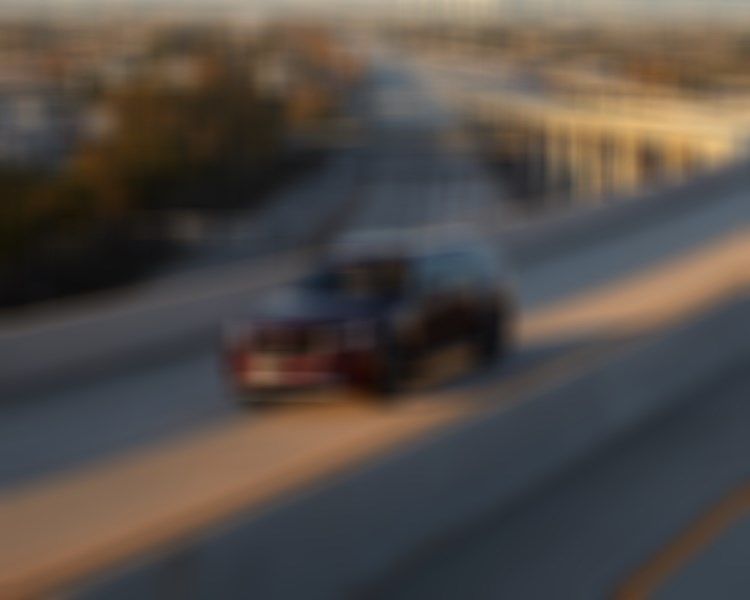 Un CX-90 rouge artisan roule sur un viaduc en béton au coucher du soleil.