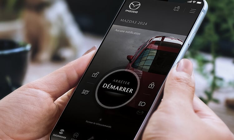 Téléphone intelligent avec l’appli MyMazda sur l’écran de démarrage du véhicule.