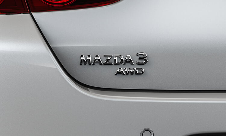 Gros plan de l’emblème AWD sur le hayon d’une berline Mazda3.  