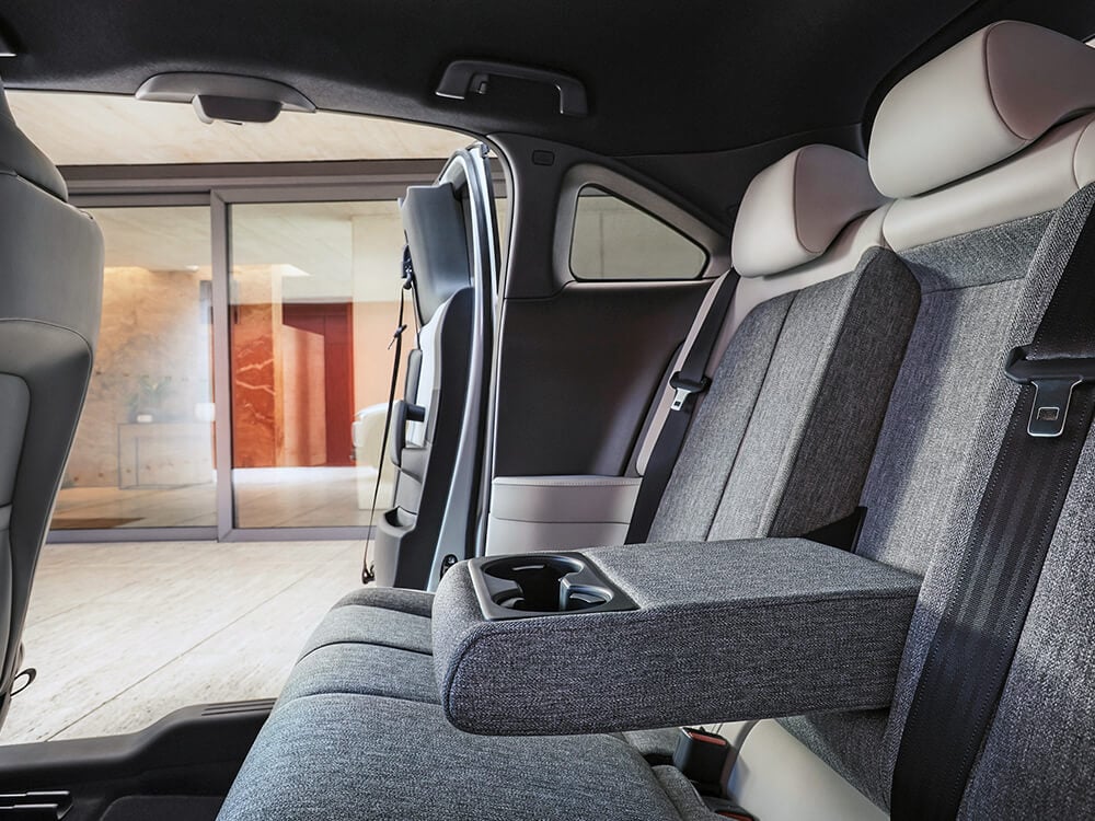 Shot of the back seat from the driver’s side with open free style doors framing up a spa’s marble-walled entrance. 
