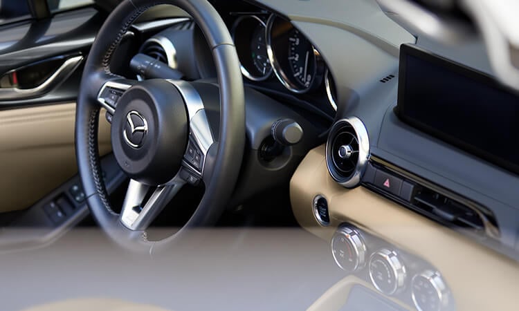 View of driver’s controls from the passenger's seat inside Tan leather interior MX-5.