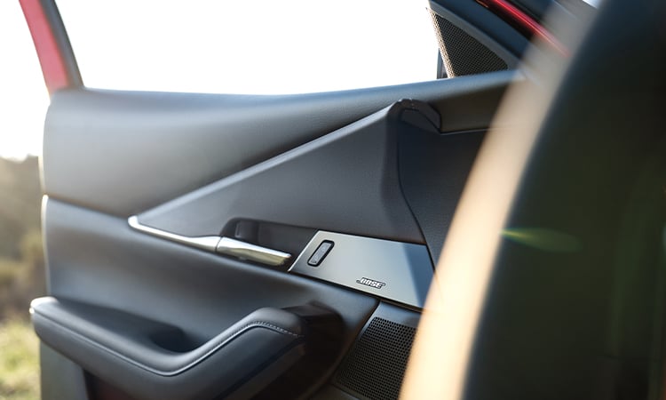 Close up of woman driving CX-30 seen through front of passenger side window.