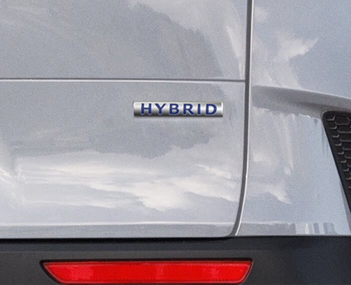 Gros plan de l’emblème « Hybrid » sur le hayon arrière droit d’un Mazda CX-50 hybride vent polaire nacré.