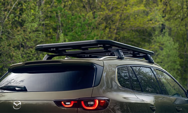 Man secures cargo with net on the CX-50’s roof rack. 