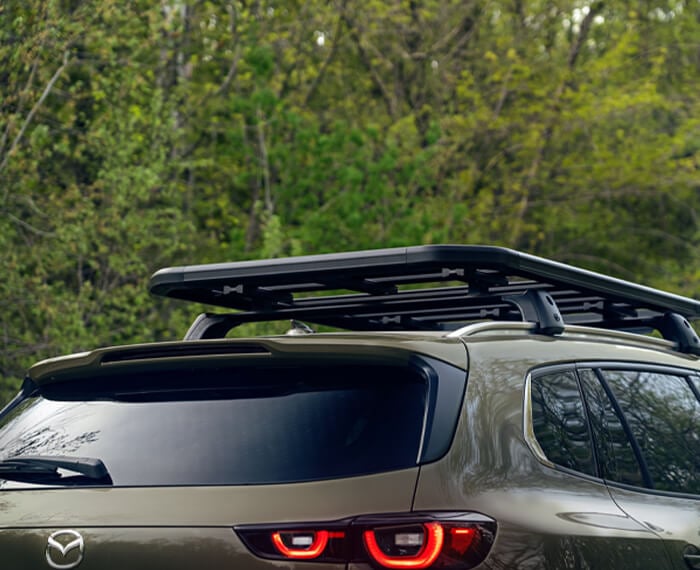 Man secures cargo with net on the CX-50’s roof rack. 