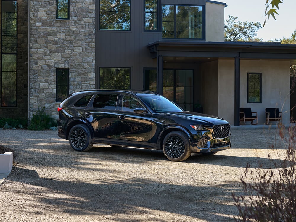 Jet Black Mica CX-70 parked in large, open driveway in front of a rural home.