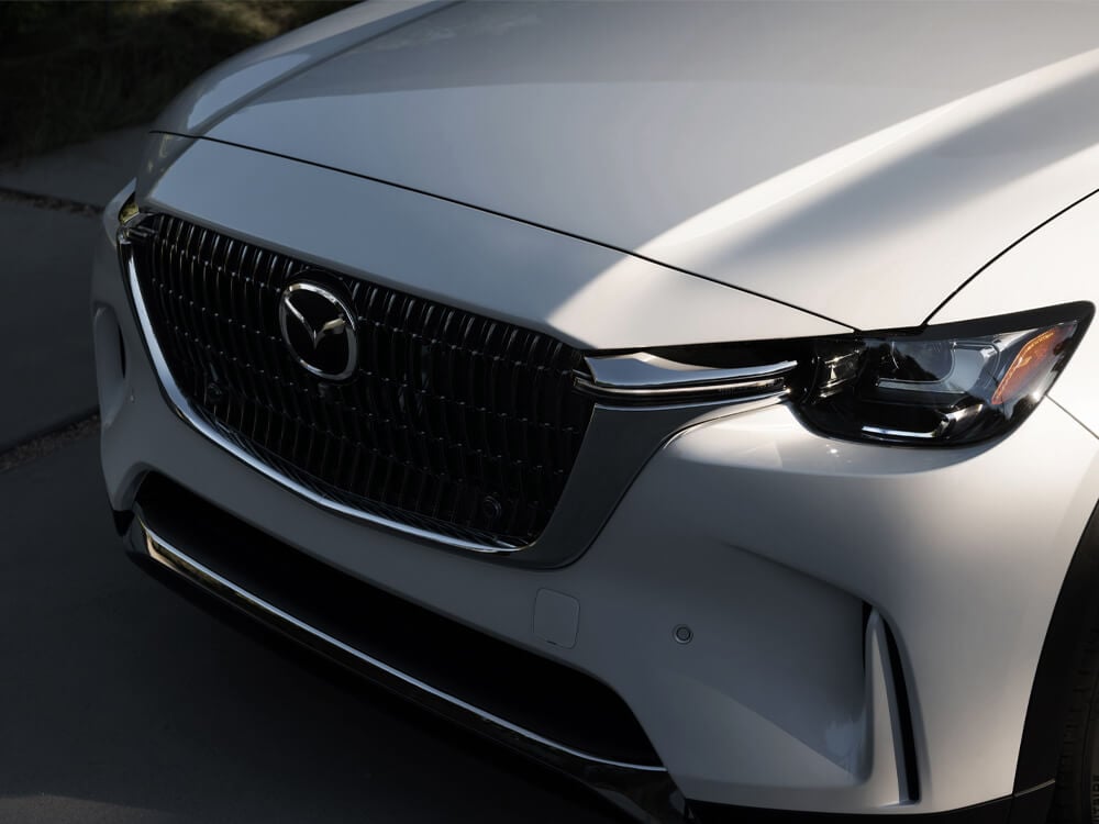 Close-up of Arctic white CX-90 front grille from above and side. 