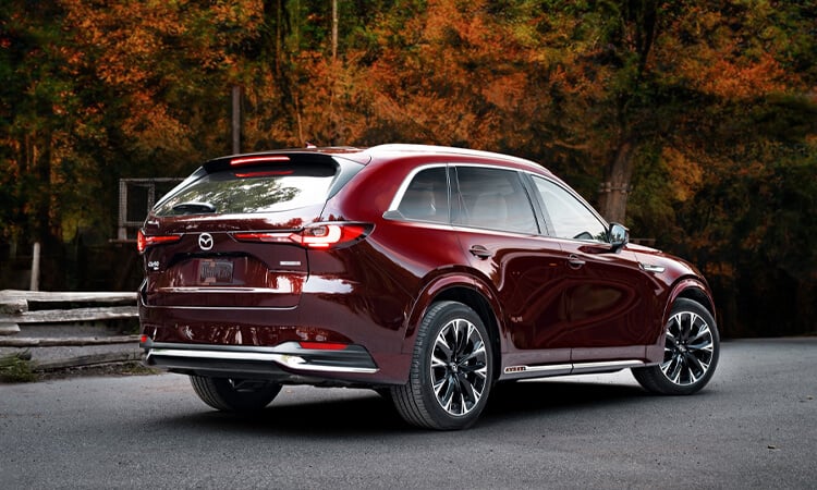 Sunlight gleaming off of the back left wheel well and taillight of an Artisan Red CX-90.