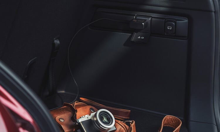 Open liftgate of CX-90 reveals brown leather camera bag and film camera in cargo area.