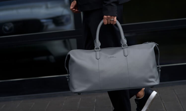 A man with hands full uses foot to activate hands-free power liftgate on Artisan Red CX-90.