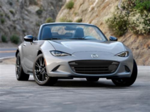 Silver MX-5 ST drives down a winding mountain road.