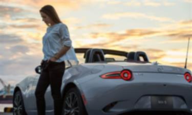 Driver with their hand in their pocket stands next to a silver MX-5 ST