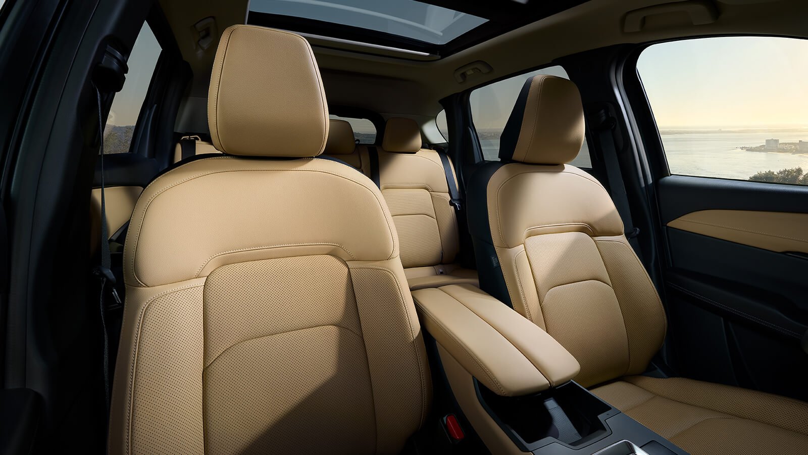 Interior view from the dashboard facing the Mazda cabin, with a body of water visible through the driver-side window.