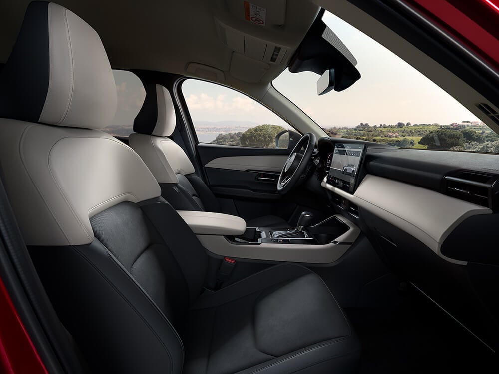 Interior of a Mazda viewed from the passenger-side door, looking toward the driver’s side with a body of water visible through the window