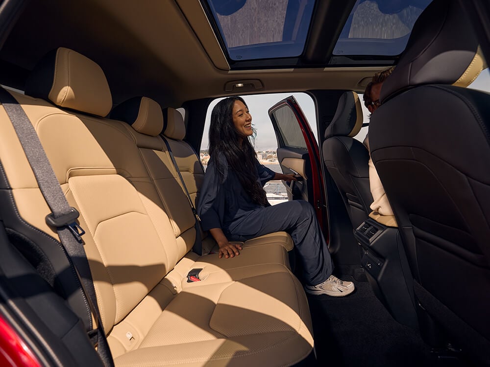 Woman getting into the back seat of a Mazda CX-5, viewed from the opposite rear door.