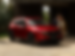 Profil latéral avant d'un Mazda CX-5 rouge vibrant cristal garé dans une allée avec un homme et une femme debout à côté.